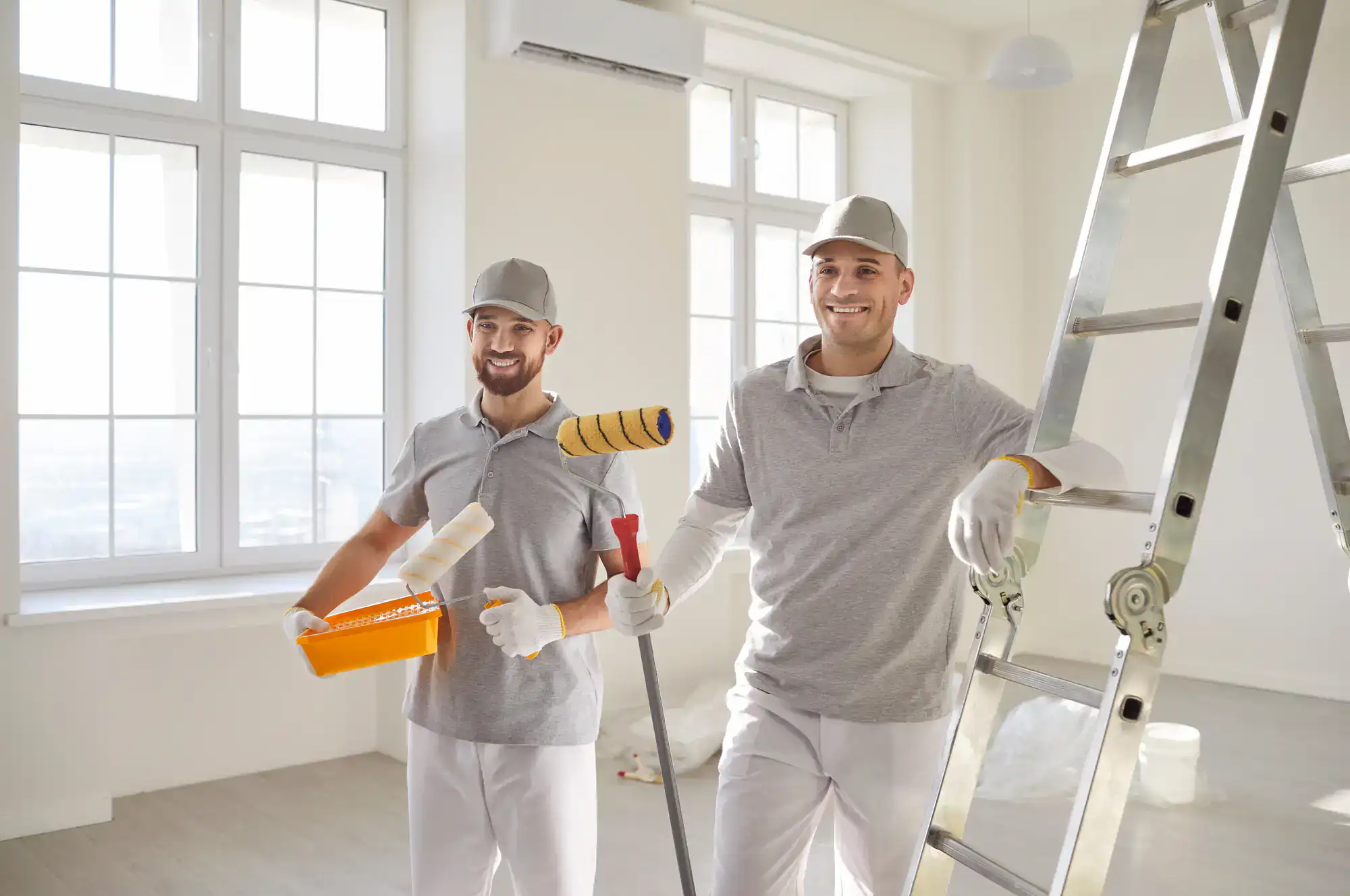 Two professional painters with painting tools in a bright room.