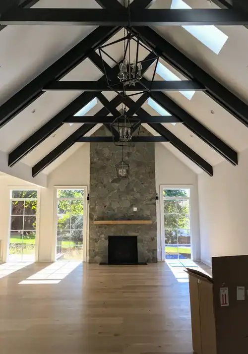Spacious living room with vaulted ceilings, stone fireplace, and large windows.