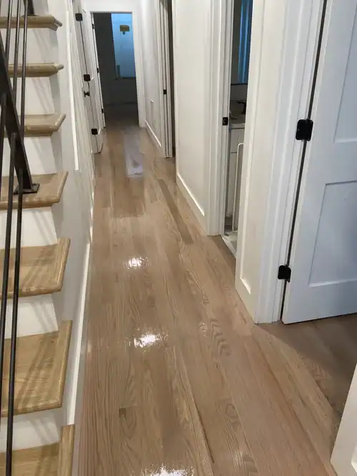 Interior hallway with polished hardwood flooring and white walls.